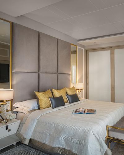 Beige velvet paneled headboard bed with gold-framed mirrors and mustard grey cushions