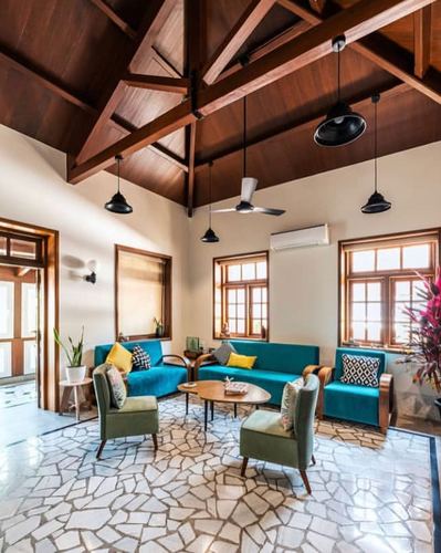 Living room with teal sofas, olive chairs, and exposed wooden truss ceiling on crazy-paved stone floor