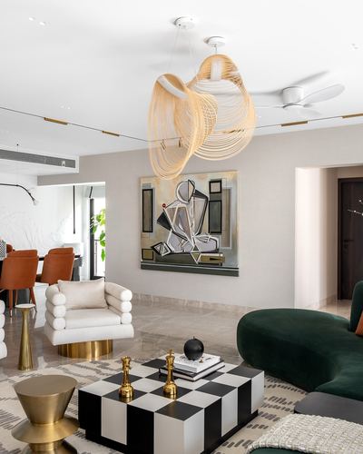 Living room with green velvet sofa, checkerboard table, and woven pendant lights under abstract art