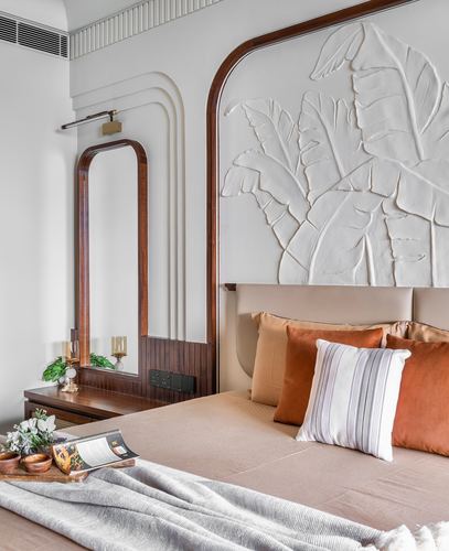 Bedroom with arched wood mirror, textured leaf relief headboard panel, and rust velvet cushions
