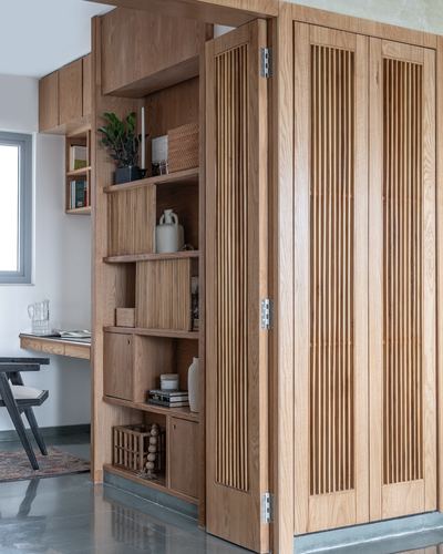Open fluted wood cabinet with display shelves beside a study desk and window