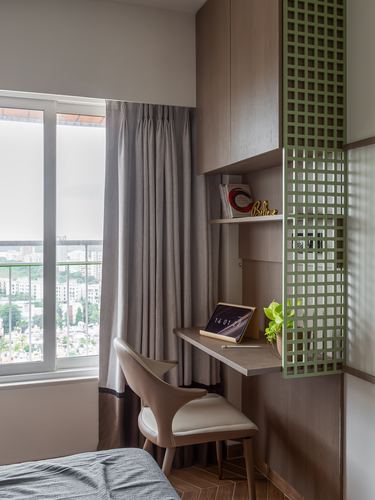 Small wall-mounted study desk beside window with green lattice screen and cane chair