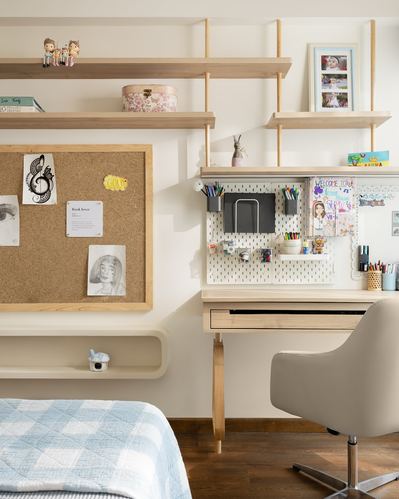 Child's study corner with pegboard, corkboard, wood shelving and desk beside a bed
