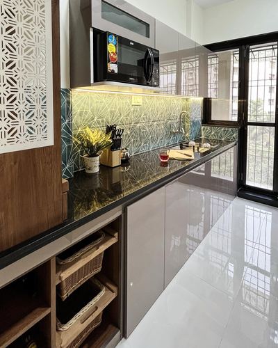 Modern galley kitchen with green geometric tile backsplash, black countertop, and wicker storage baskets