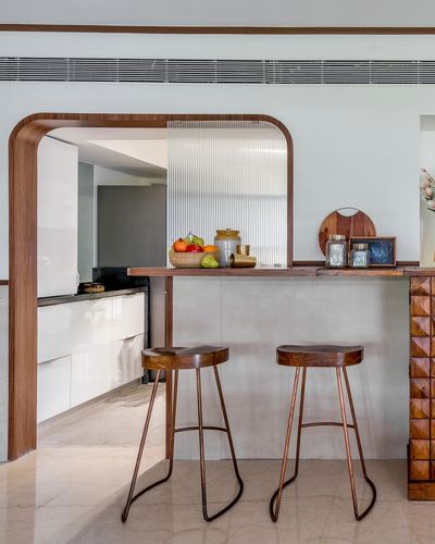 Arched wood-framed kitchen opening with fluted glass, stone counter, two wooden bar stools