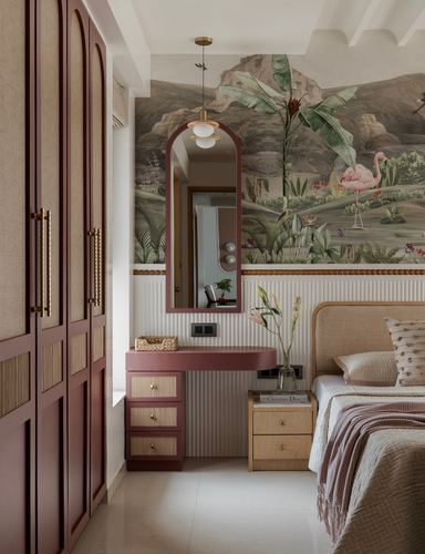 Maroon wardrobe and vanity beside bed with mural wallpaper and arched mirror