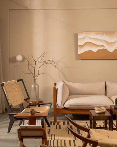Warm-toned living room with cane chairs, linen sofa, and abstract landscape painting on beige wall