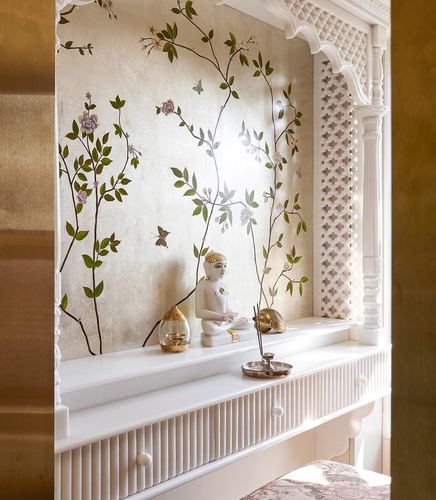 Niche with hand-painted floral mural, Buddha statue, and fluted white cabinetry framed by carved archway