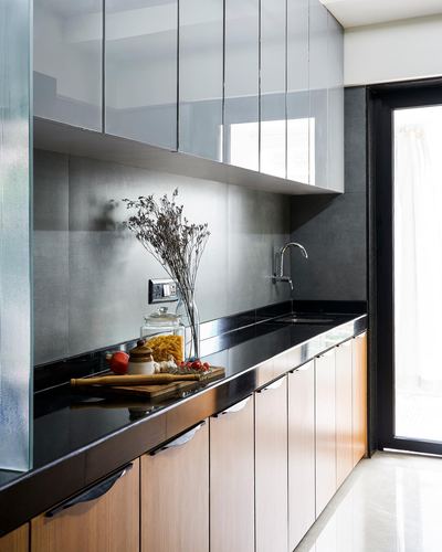 Modern galley kitchen with glossy white uppers, dark backsplash, black countertop and wood-front lower cabinets