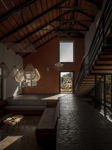 Double-height brick living room with sunken seating and clustered woven pendant lights beside staircase