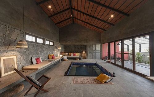Stone-walled living room with pitched terracotta tile roof and sunken plunge pool at center