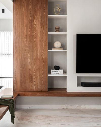 Wooden paneled wall with recessed display shelves beside a wall-mounted TV in a minimalist living room