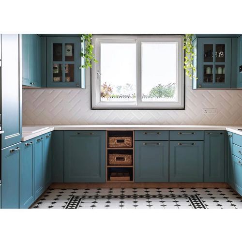 Teal U-shaped kitchen with herringbone tile backsplash and patterned floor beneath a central window