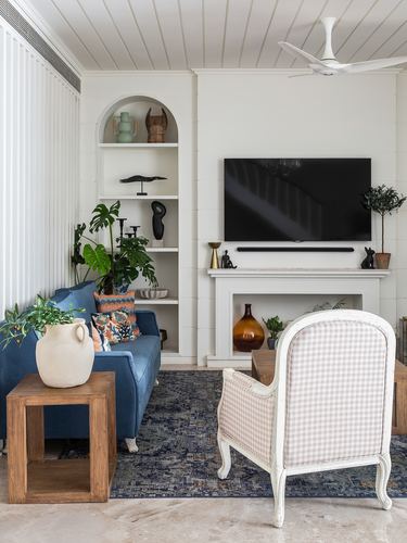 Living room with arched shelving, fireplace, blue sofa, and gingham armchair on navy rug