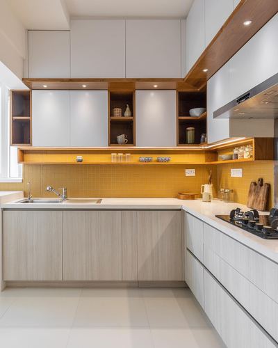 L-shaped modern kitchen with white cabinets, wood accents, and mustard tile backsplash