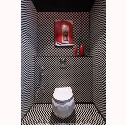 Powder room fully clad in black and white checkerboard tile with a red archway artwork above the toilet