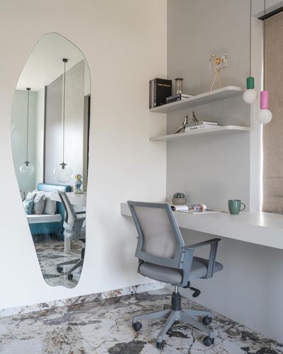 Study nook with mesh chair, floating desk, and organic mirror reflecting bedroom beyond