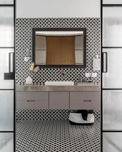 Symmetrical bathroom vanity framed by reeded glass doors and geometric black-white tile