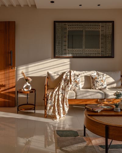 Sunlit living room with cane-backed sofa, floral cushions, and framed textile art on wall
