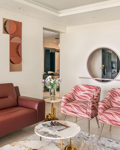 Living room with maroon sofa, patterned pink armchairs and a circular wall niche