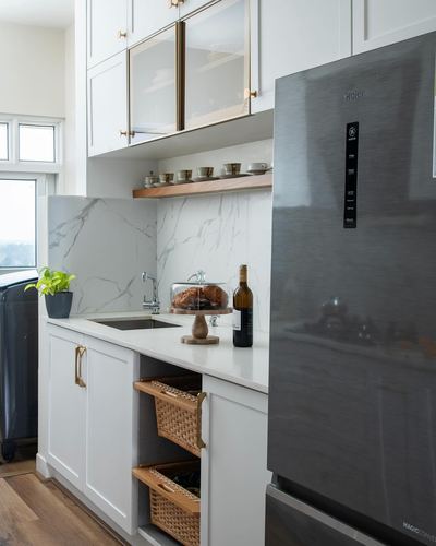 White minimalist kitchen counter with marble backsplash, wicker drawers, and stainless steel refrigerator