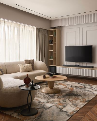 Neutral living room with curved beige sofa, round wood coffee table, marble-pattern rug, and fluted TV console