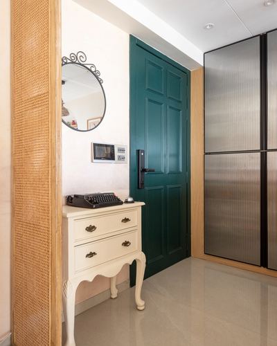 Entryway with cane panel, round mirror, vintage typewriter on white console, and green paneled door