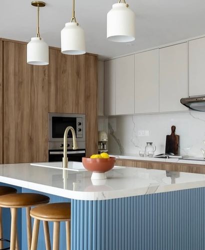 Contemporary kitchen with wood cabinetry, marble backsplash, and a fluted blue island under brass pendant lights
