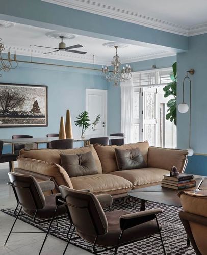 Living and dining room with blue walls, camel sofa, brown armchairs and chandeliers