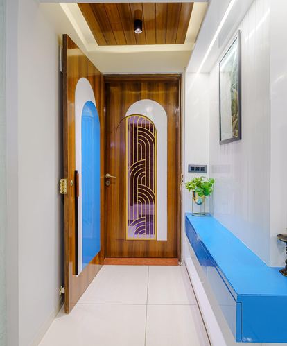 Wooden art deco entry door with arched stained glass panel beside a glossy blue floating console