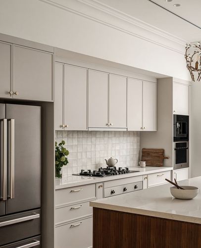 Beige shaker cabinet kitchen with tiled backsplash, stainless fridge and wood island counter