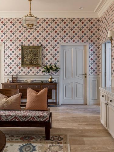 Patterned foyer with brass pendant, wooden console, and cushioned daybed in warm tones