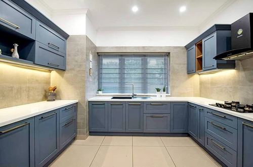 U-shaped kitchen with slate blue cabinets, white countertops, and a window above the sink