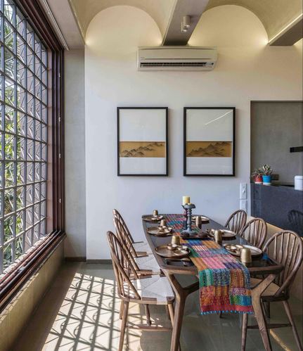 Dining room with wooden table, windsor chairs, kantha runner, vaulted ceiling and jaali window casting shadows
