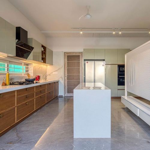 Island kitchen with wooden drawers, sage cabinetry, and grey stone flooring under track lighting
