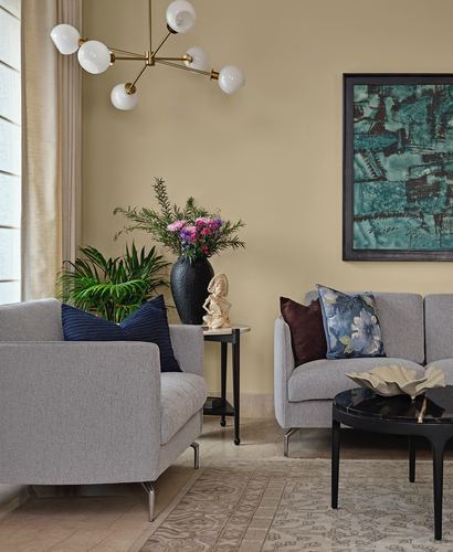 Beige living room with grey sofas, brass sputnik chandelier, teal abstract artwork, black marble coffee table