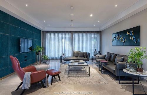Living room with teal velvet wall, leather sofas, and abstract wall art
