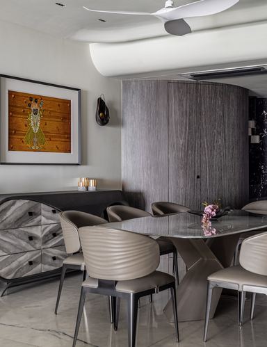 Dining area with oval marble table, ribbed leather chairs, curved wood wall and sculptural ceiling.