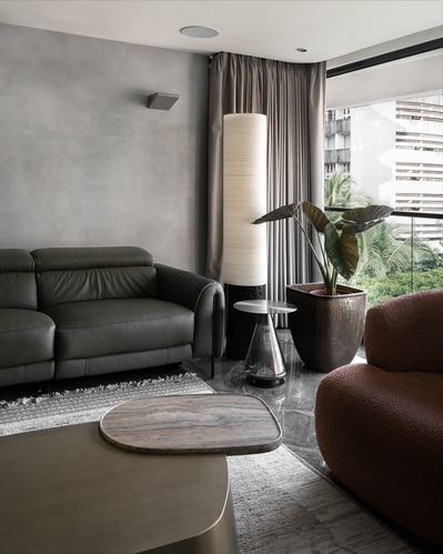 Grey living room with olive leather sofa, rust boucle armchair, and marble side table by window