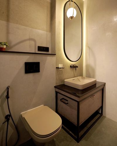 Bathroom with wall-hung toilet, backlit oval mirror, and metal-framed vanity with vessel sink