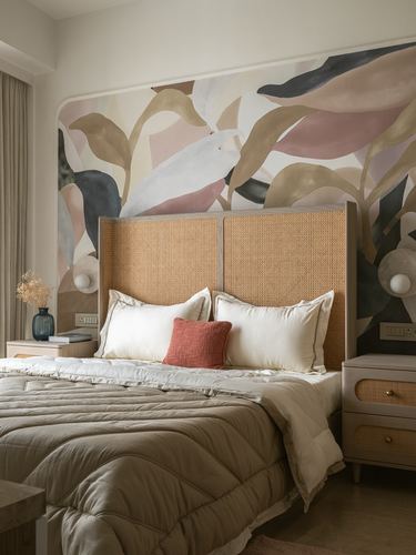 Bed with woven cane headboard against a large botanical leaf mural in soft earthy tones