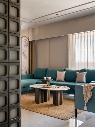 Teal sectional sofa with sculptural coffee tables viewed through a textured metal jali partition