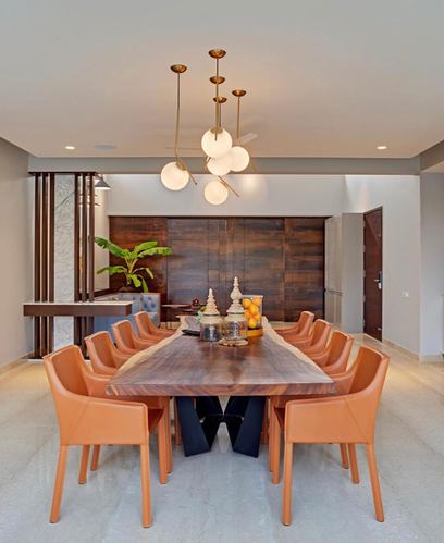 Dining room with live-edge wood table, tan leather chairs, and a brass globe pendant chandelier
