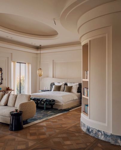 Curved bedroom with fluted wall, upholstered bed, parquet floor, and marble-edged bookshelf niche