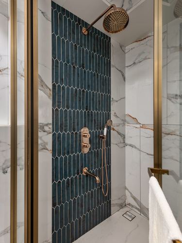 Marble shower with brass fixtures and a teal picket tile accent wall in Kolkata home