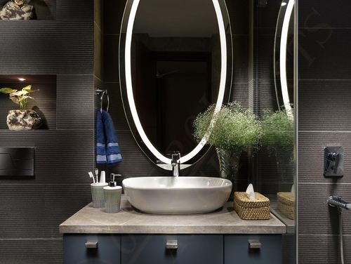 Dark bathroom vanity with backlit oval mirror, vessel sink, and stone countertop