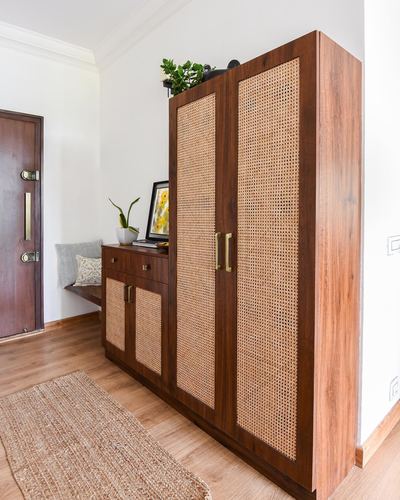 Foyer with tall cane and wood wardrobe beside wooden entry door and bench