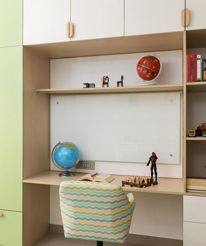Kids study nook with plywood shelving, whiteboard, globes and a chevron-patterned chair
