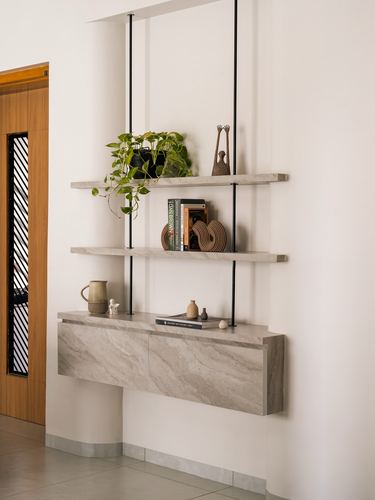 Wall niche with stone floating shelves and console holding plants, books and ceramics beside a wooden door