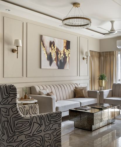 Beige living room with paneled walls, gold artwork, chandelier, and mirrored coffee table